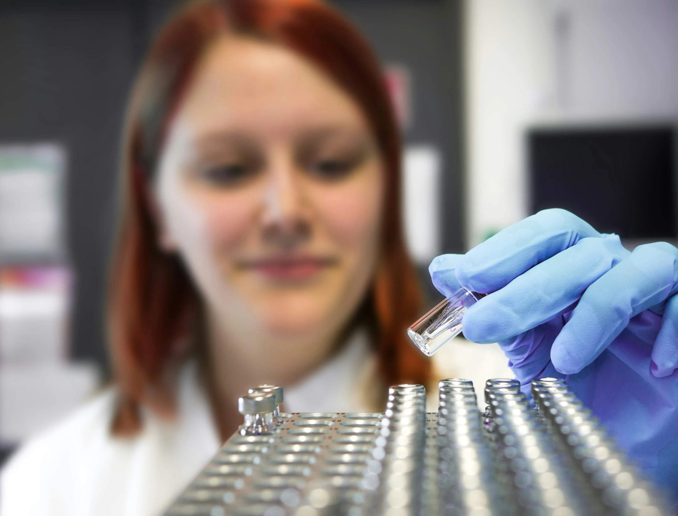 a woman wearing gloves holds a small device in a gloved hand