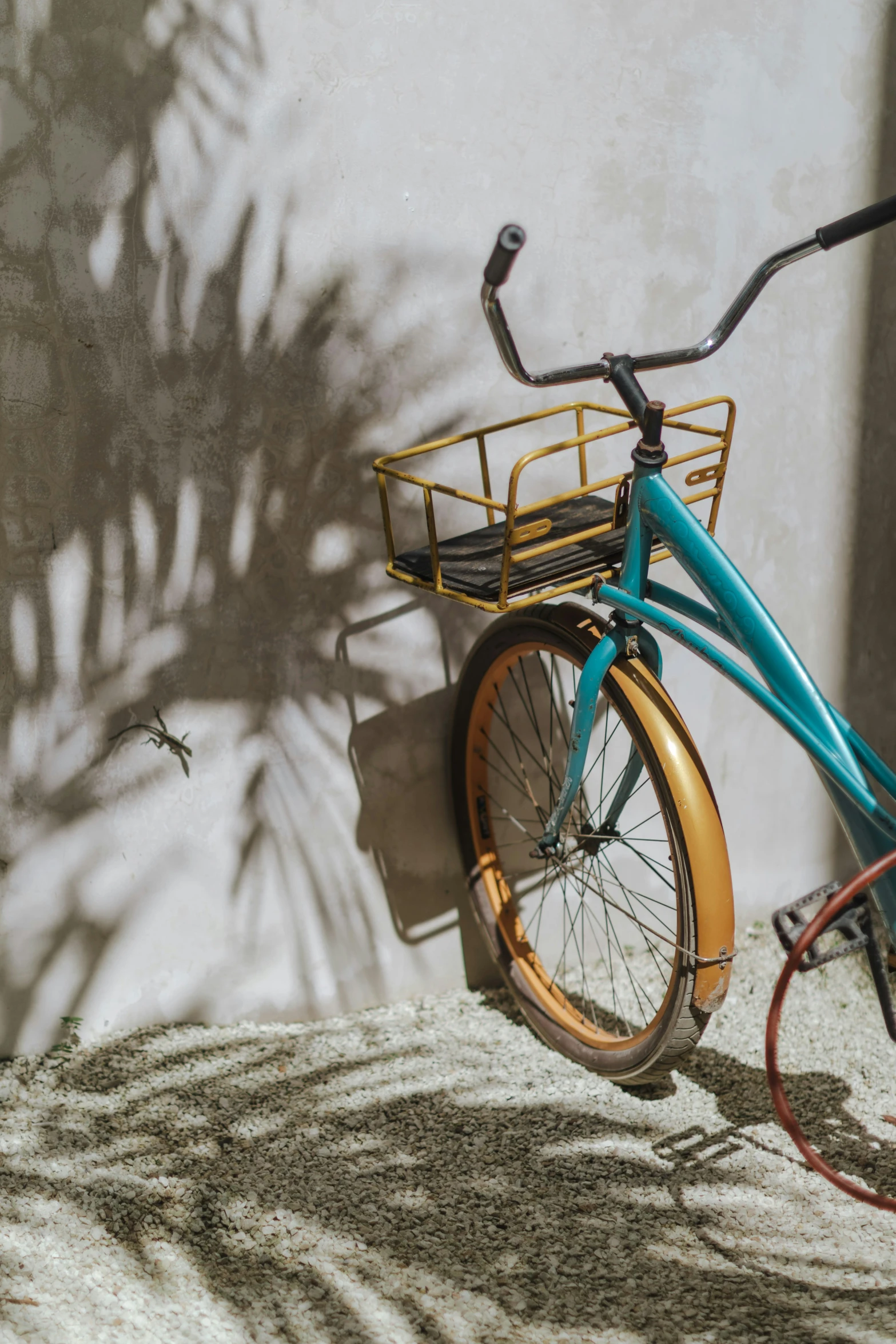 an orange, blue and black bike with basket parked in front of a white building