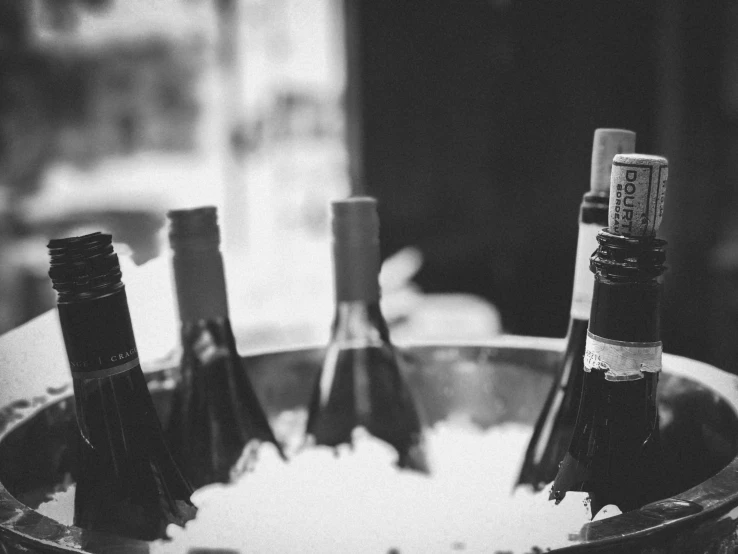 four bottles of wine sitting in a small metal barrel