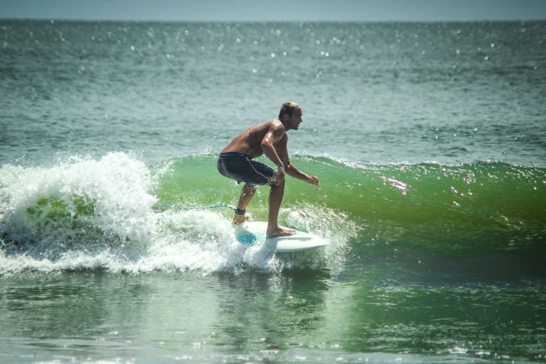 a shirtless man riding a surfboard on top of a wave