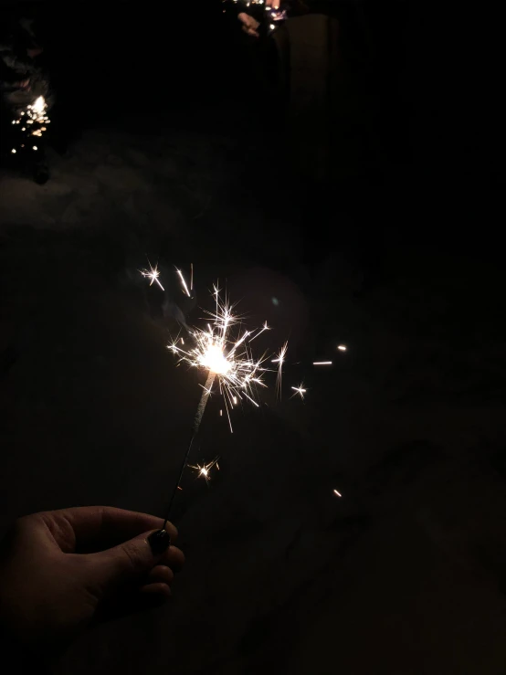 a hand is holding a sparkler with small pieces of firework