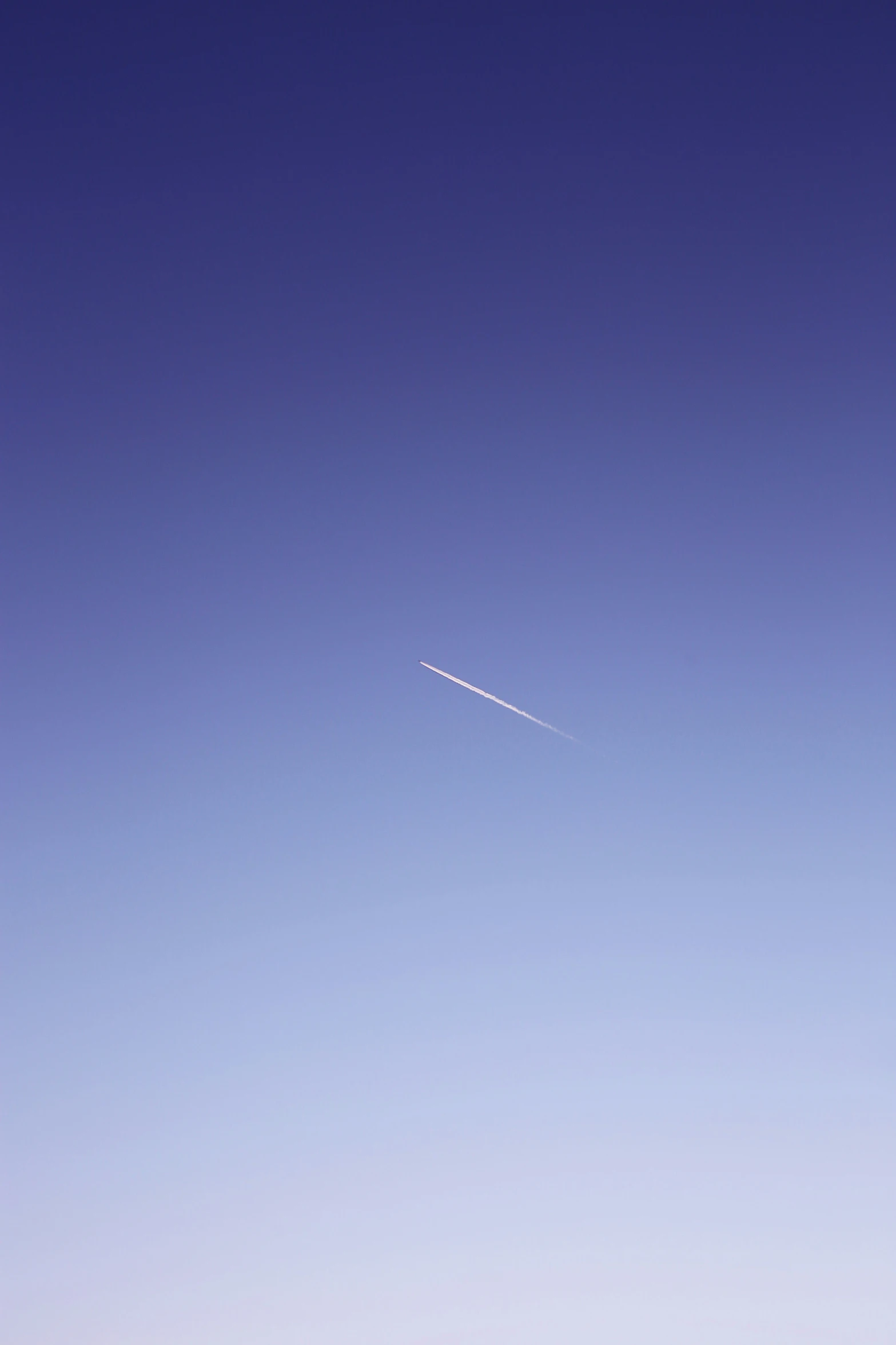 a distant plane flies through the blue sky