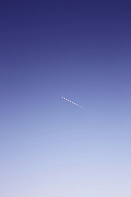 a distant plane flies through the blue sky