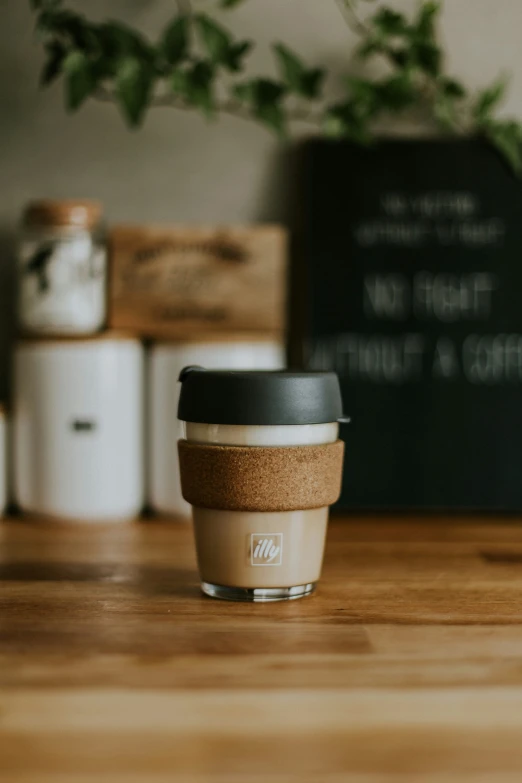 coffee cup with cork lid sitting on top of wooden table