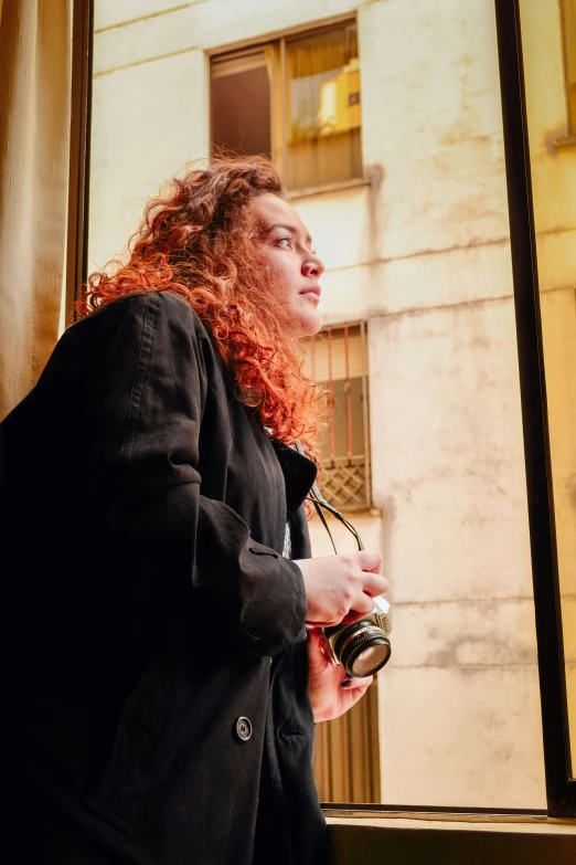 woman with red hair looking out a large window