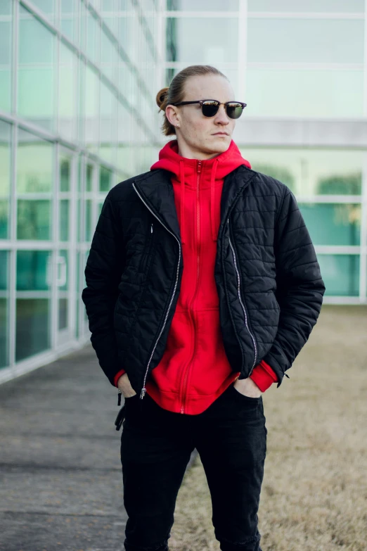 a man in red jacket and black pants standing in front of a building