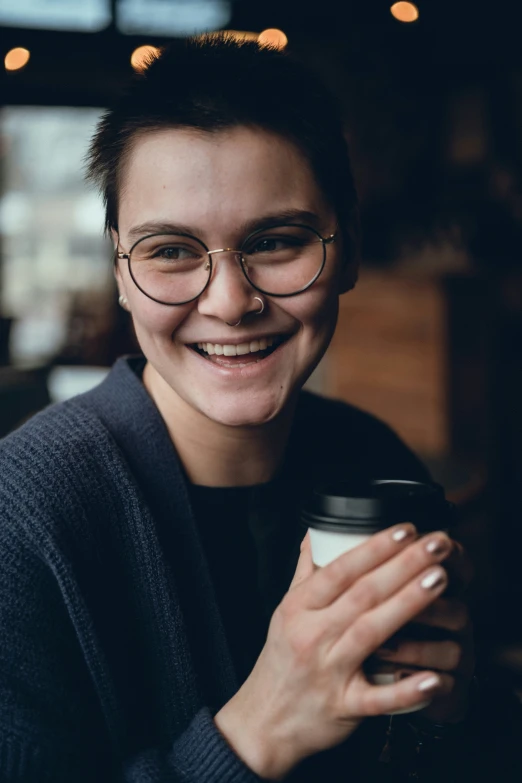 a close up of a person smiling holding a coffee cup