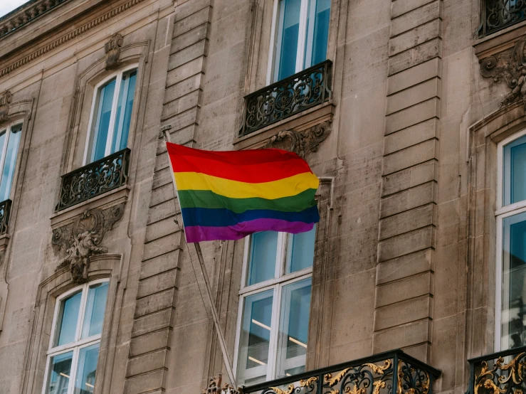 a rainbow flag waving in front of a stone building