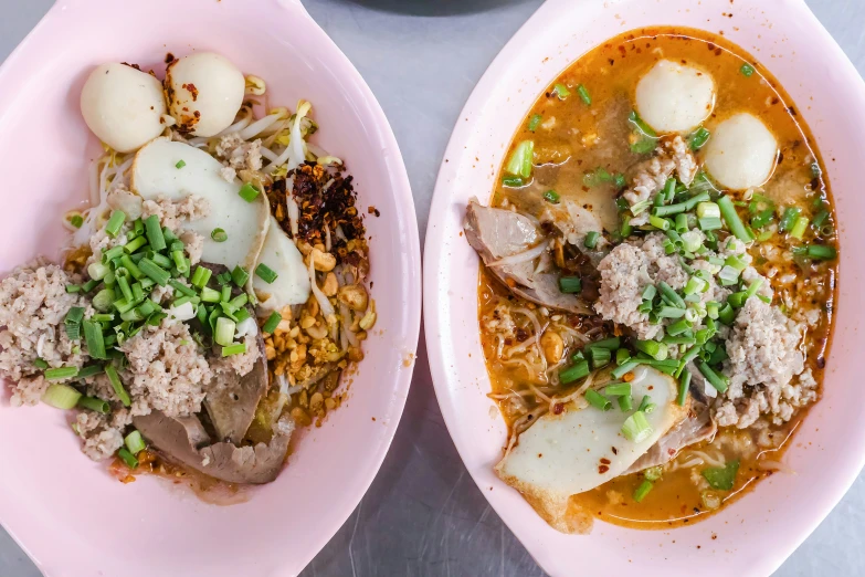 two large pink plates have some meat, vegetables and rice in them