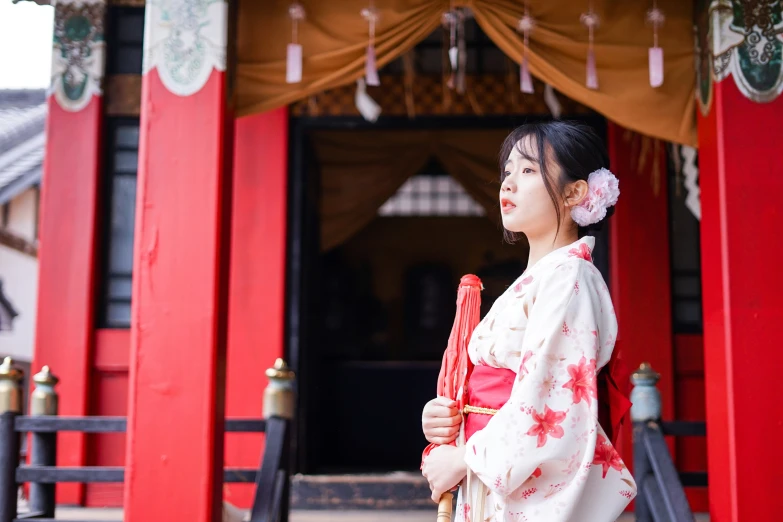 a  in traditional kimono standing in front of a shrine