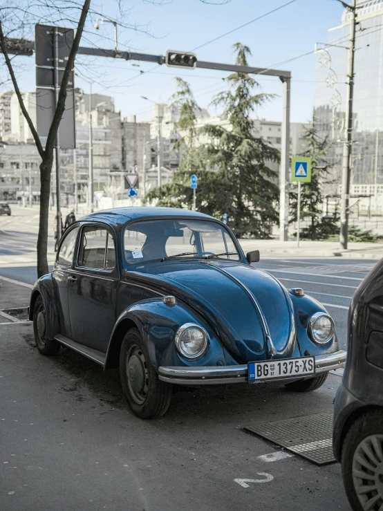 the classic blue volkswagen beetle is on the street