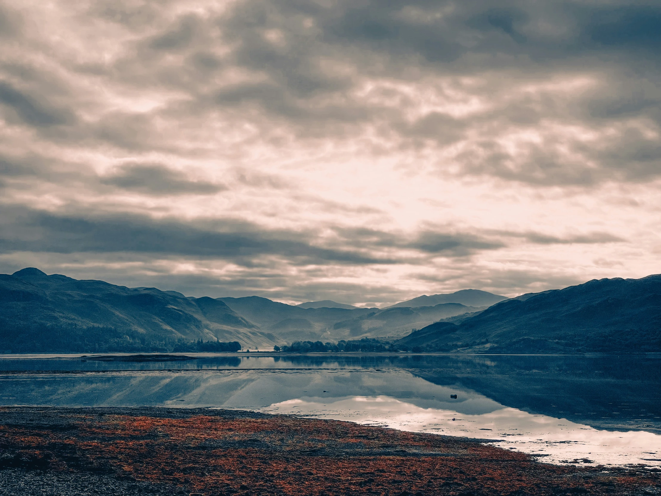 an empty lake with a snow covered mountain behind it