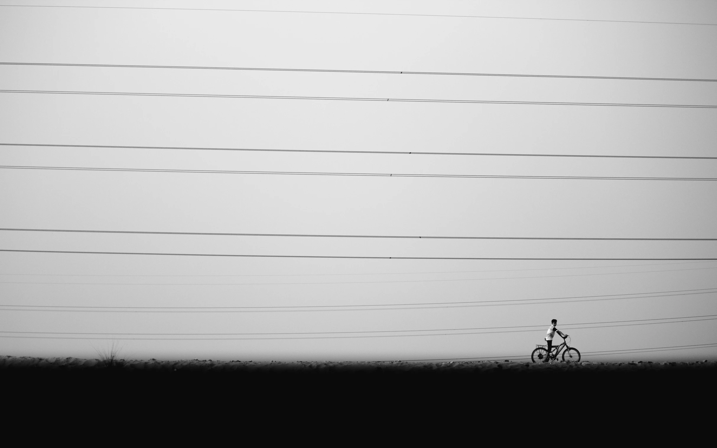 man on bicycle in front of telephone poles with sky in background