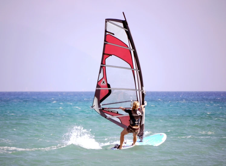 a woman windsurfing on a calm body of water