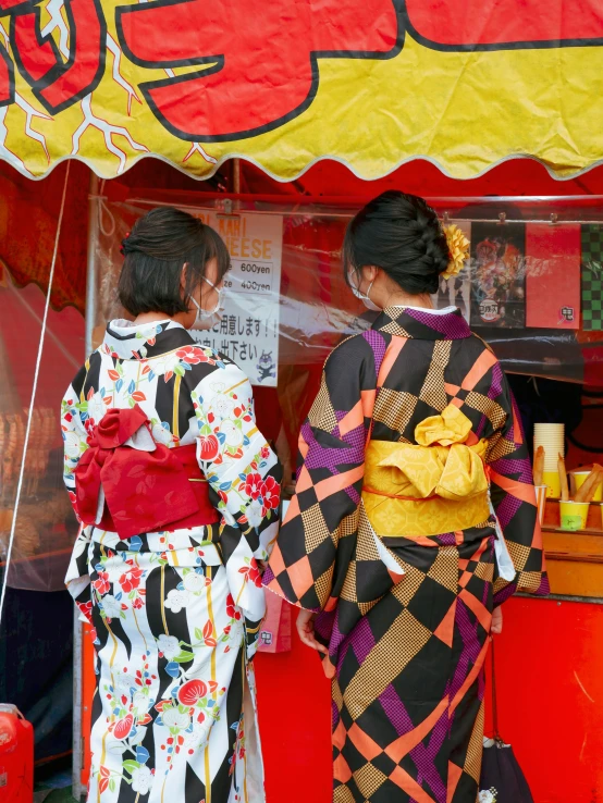 two geisha women are standing under a tent