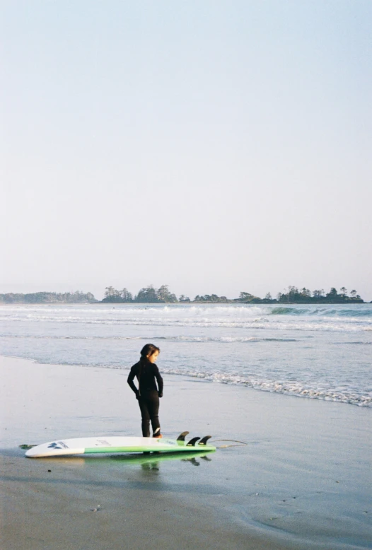 there is a man standing on the surfboard at the beach