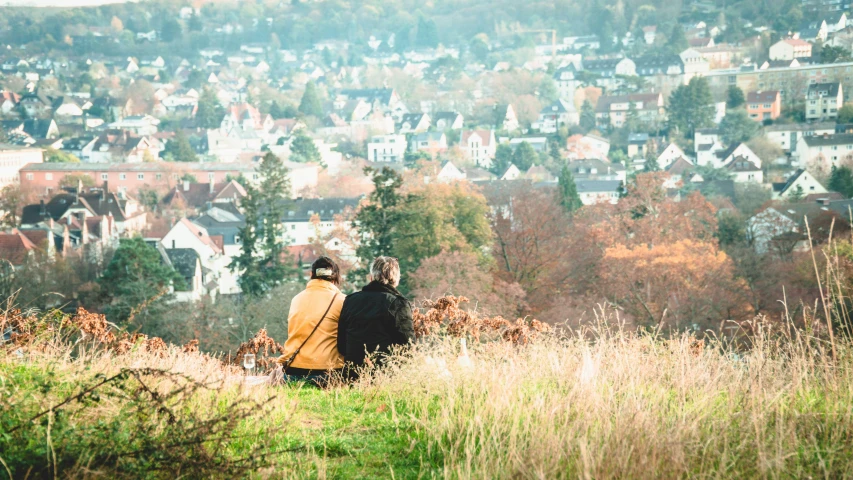 two people on top of a hill overlooking a town