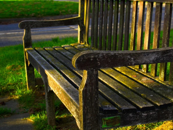 a wooden bench sitting next to a grassy field