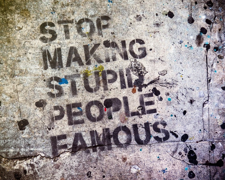 the words stop making stupid people famous are spray painted on an area