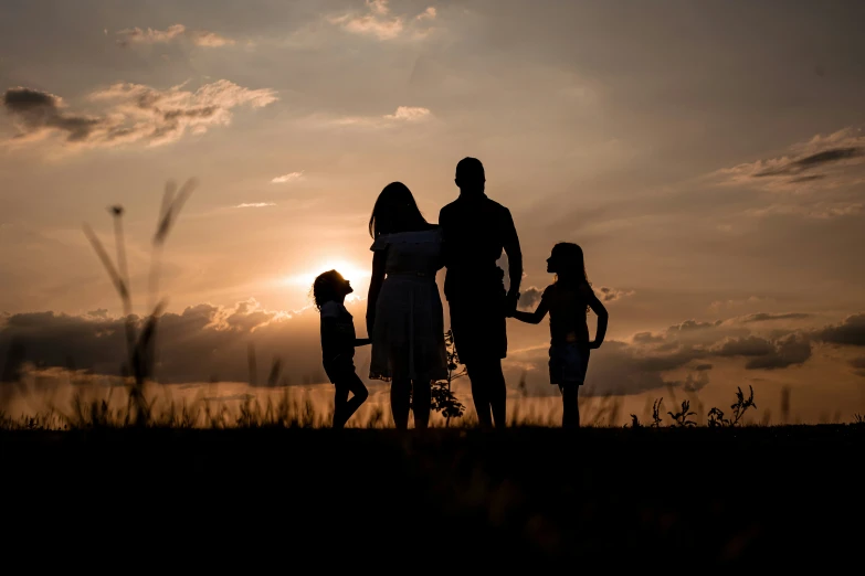 a family walking in an open field at sunset