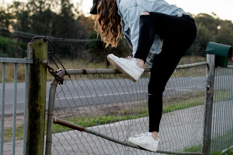 a girl balancing on a railing in front of trees