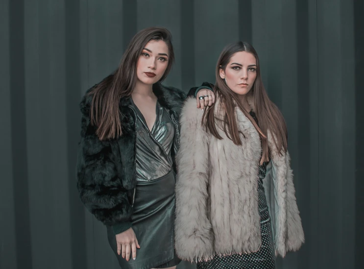 two women posing in dresses and furs for a po