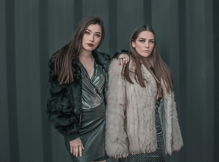 two women posing in dresses and furs for a po