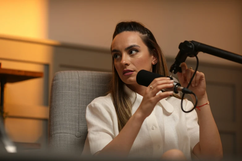 a woman holding a microphone sitting in a chair