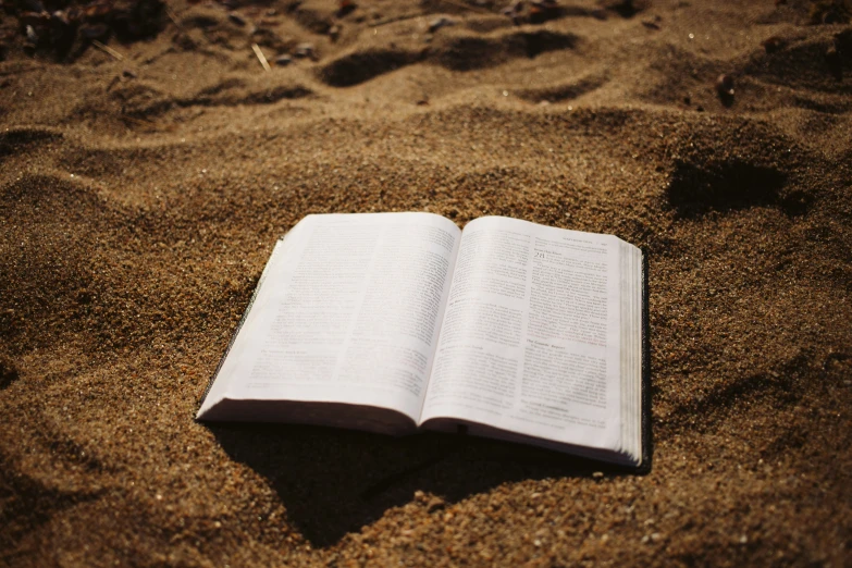 an open book sitting on the sand