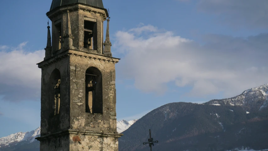a very old looking church tower against a background of mountains