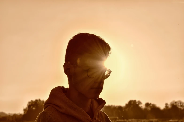 a man that has his eyes open and sun glaring in the background