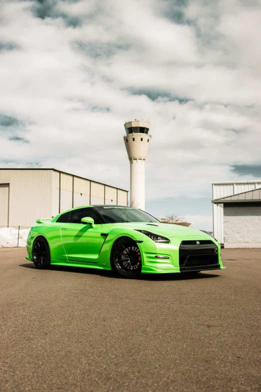 a lime green sports car in front of an airport control tower