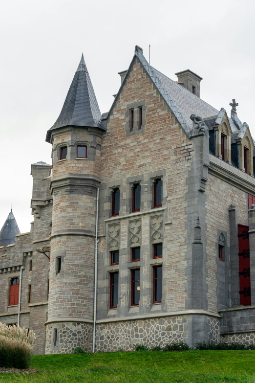 a castle building with three towers sitting in the grass