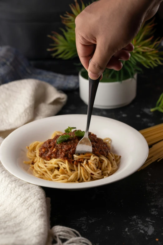 someone using a ladle to cut up spaghetti in the bowl