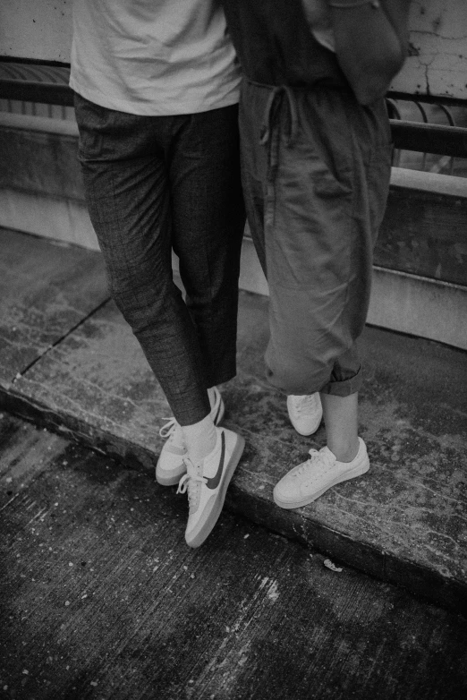 two people with their legs crossed standing next to a fire hydrant