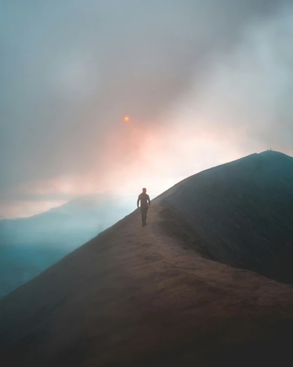 the person standing at the top of a hill on a foggy day