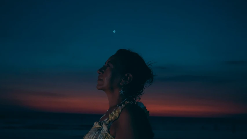 a woman stands in the evening and watches the sun set