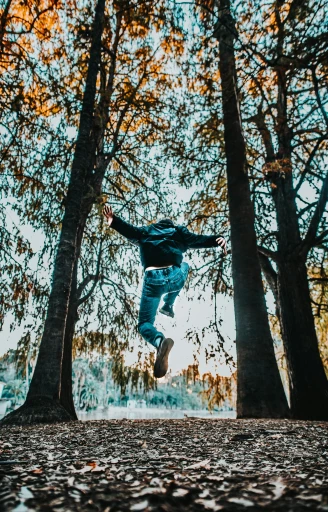 a young man jumping into the air by himself in the woods