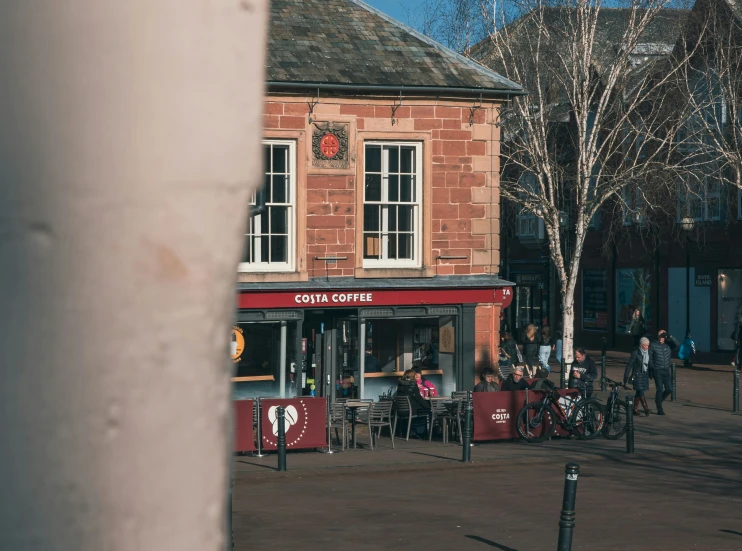 a group of people sitting at small tables next to a tree