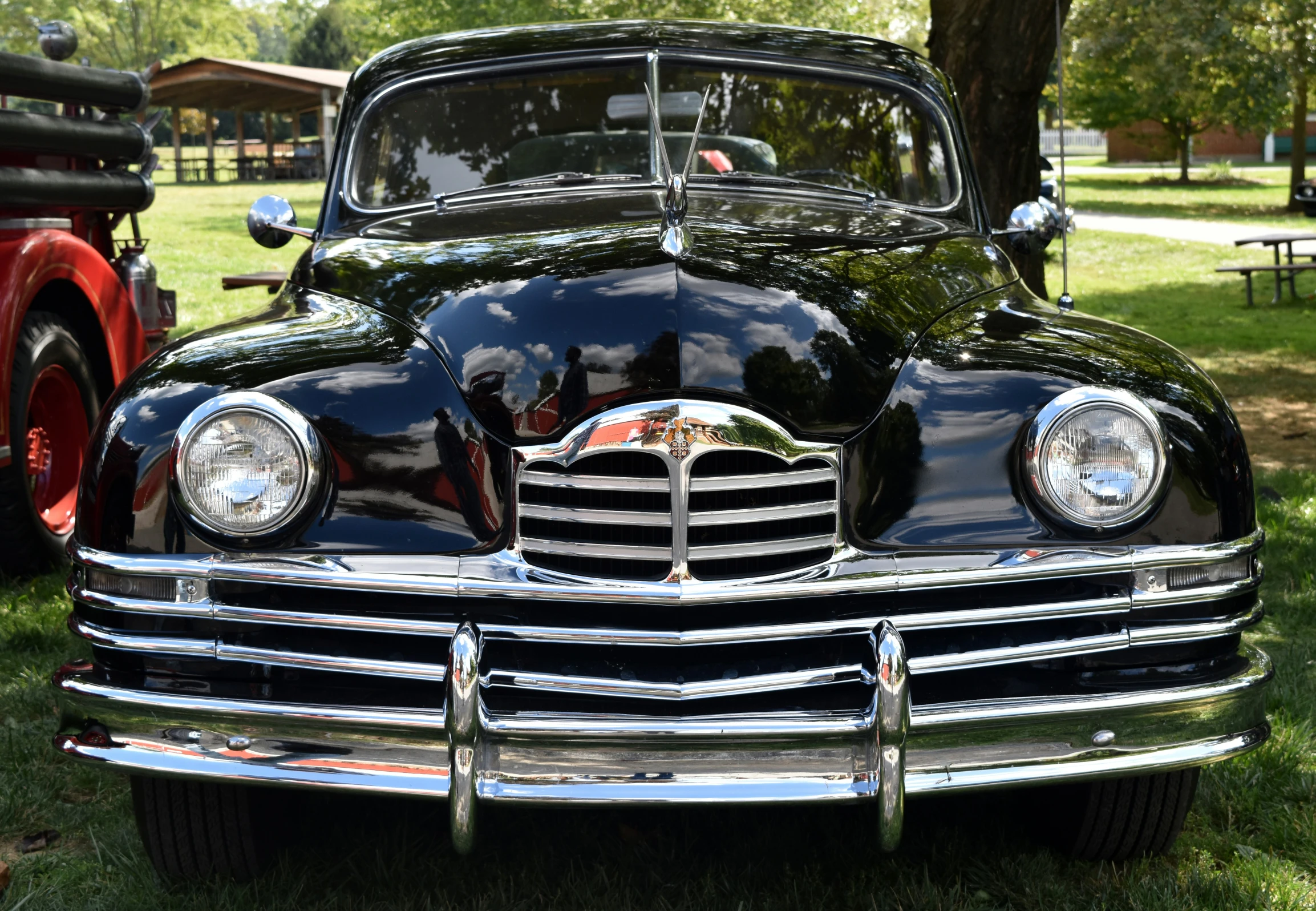 an antique car sits in the grass near trees