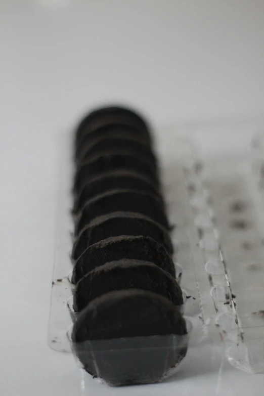 six black icing pieces are sitting on a plastic plate