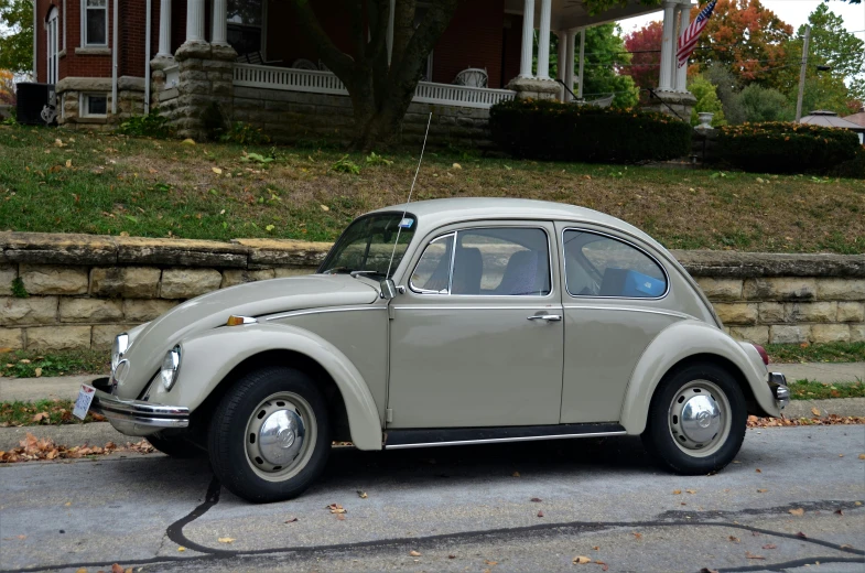 a white beetle parked outside a house near grass