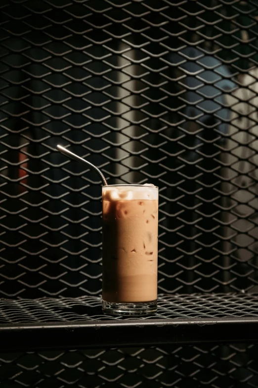 a glass of milkshake with a straw in it is next to an object