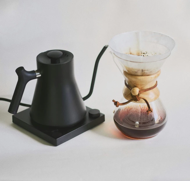 coffee pourfection pouring tea into a cup next to a smaller glass object