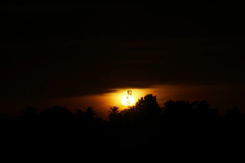 the sun shining through the dark clouds over the trees