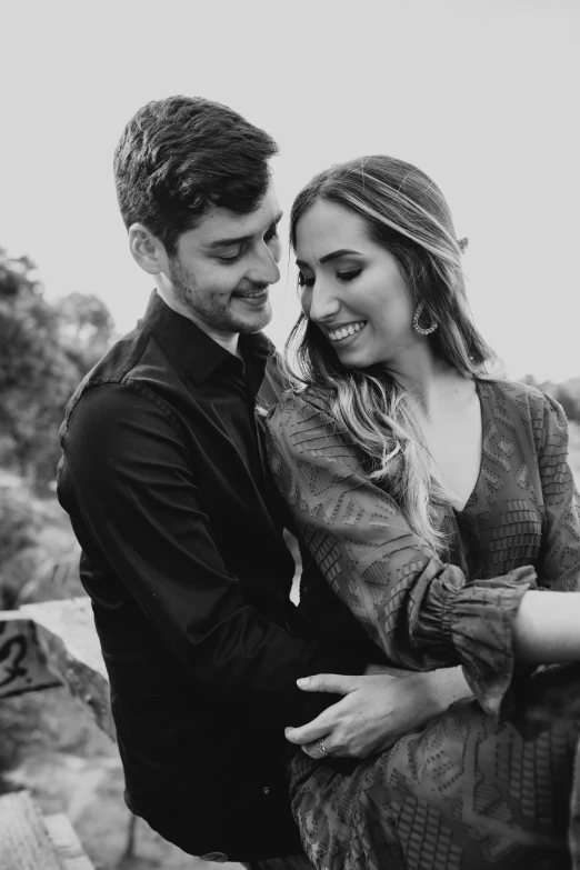 a black and white image of a young couple emcing while the girl is holding her arm around the mans waist