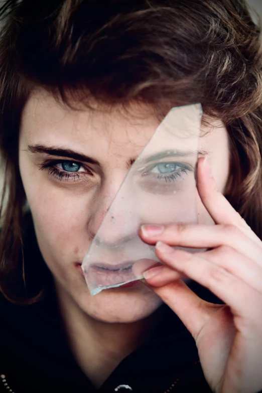 a woman looking through the glass while holding her face