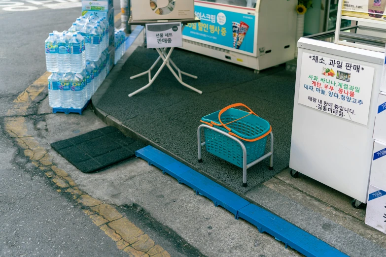 a small blue basket sitting on the ground next to a small white cooler