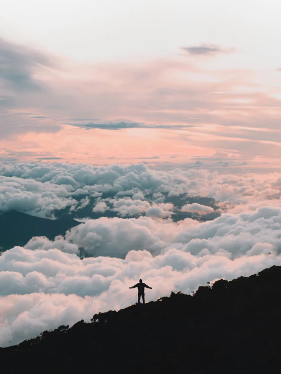 a man on the side of a mountain with clouds below