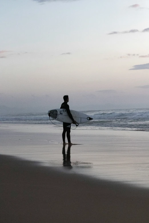 a person walking on the beach with a surfboard